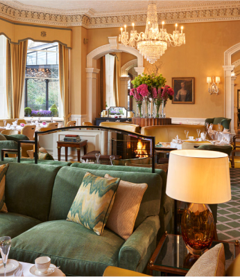 Elegant lounge area with green sofas, chandelier, and floral arrangements